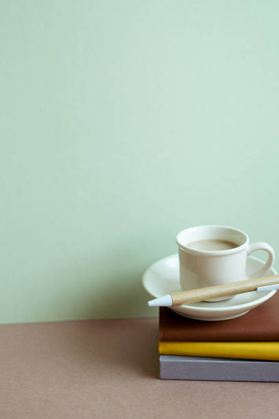 istock Stack of notebook and pen, cup of coffee on desk. mint wall background. workspace, copy space 1453034539