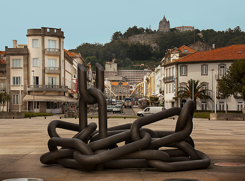 Viana do Castelo, Portugal-May 5, 2011: Chains part of April 25th memorial, sculpture in Praça da Liberdade , sculptor José Rodrigues,, Viana do Castelo, Portugal. Santa Luzia hill sanctuary in the background, incidental people.