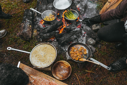 Campfire  smoking salmon in pan, near the fire outdoors. bushcraft, adventure, tea, knife and camping concept