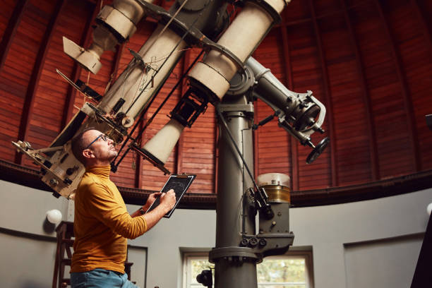 Astronomer with a big astronomical telescope in observatory doing science research. stock photo