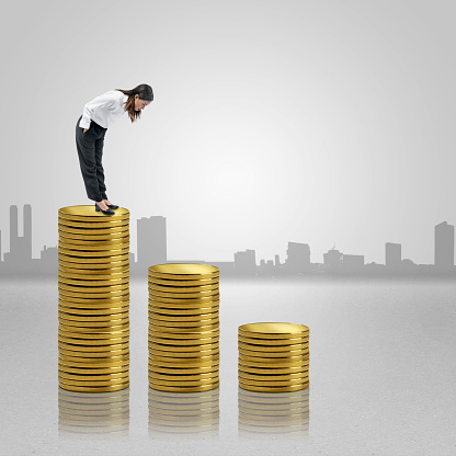 Asian businesswoman standing and looking down the coin stack with colored background