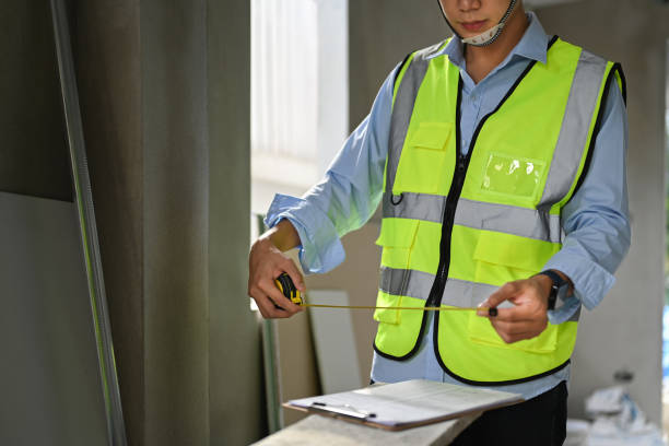 istock Engineer or inspector working with blueprints with measure tape in his hands while standing in building construction. 1453046807