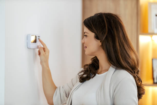 A happy woman is turning heat on in her apartment. stock photo