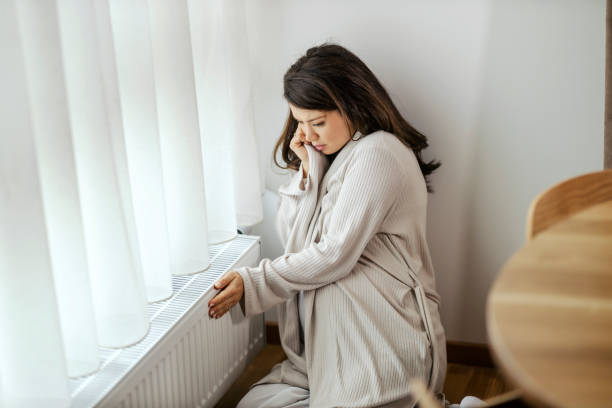 istock A pregnant woman is checking on radiator if it is warm. 1453048131