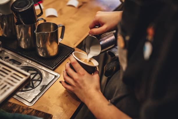 barista versant du lait pour faire une tasse de café cappuccino dans un café - bar à expresso photos et images de collection