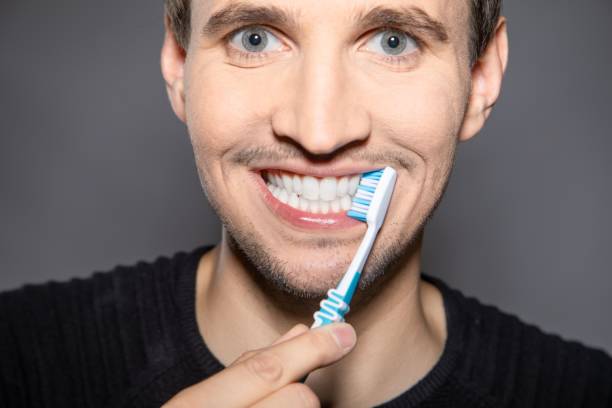 istock Man with toothbrush on side of white teeth with smiling mouth brushes interdental space carefully 1453051321