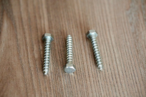 Three lag bolts screws on a wooden table