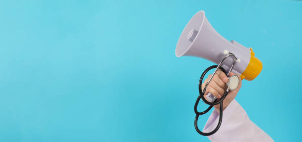 The doctor's hand is holding a megaphone and stethoscope on blue background.