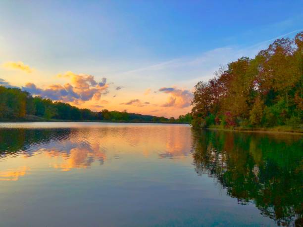 istock Breathtaking cloudy sunset sky reflected in the river flowing through the colorful trees in autumn 1453061698