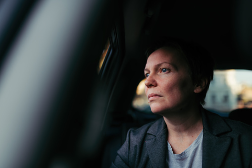 Worried businesswoman waiting in the car and looking out the window, selective focus