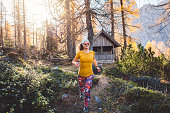 Smiling woman hiker with sunglasses running trough the autumn forest on a sunny day