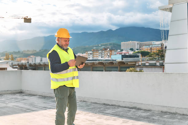 istock Middle aged bearded supervisor in hardhat and safety vest with tablet on building site. Structural engineer or architect monitors the progress of the work on construction site. 1453066034
