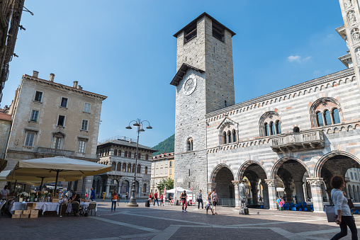 Como, Italy - June 9, 2017:  Como city, square del Duomo with the palace and tower of the Broletto from 1215. Square with restaurants and cafes