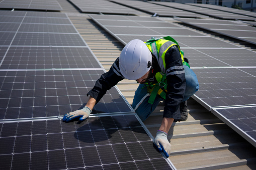 Blue collar worker install solar panel on rooftop. New alternatives, environment and electricity power.