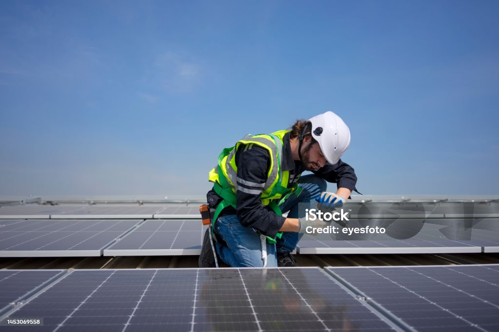 Blue collar worker install solar panel on rooftop. Blue collar worker install solar panel on rooftop. New alternatives, environment and electricity power. 20-24 Years Stock Photo