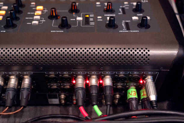 Instrument audio jack connectors inserted into channels on a mixing desk in a recording studio.\nBack panel of audio equipment. Audio connectors, cables and connectors.