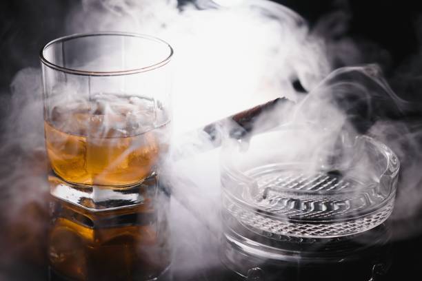 istock Glass of cold whiskey with cigar on dark background 1453086966