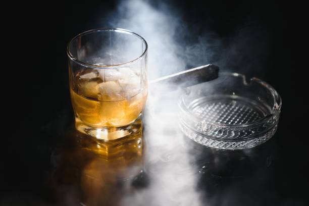 istock Glass of cold whiskey with cigar on dark background 1453087018