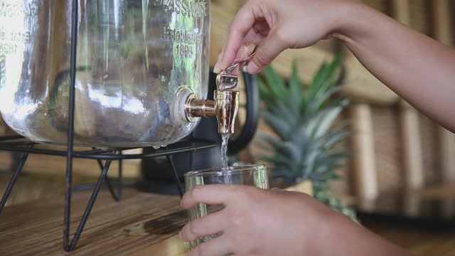 Unrecognizable Woman Taking Drinking Water From a Glass Dispenser