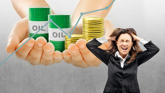 Asian businesswomen stress with the increase in oil prices on a colored background. Oil Crisis