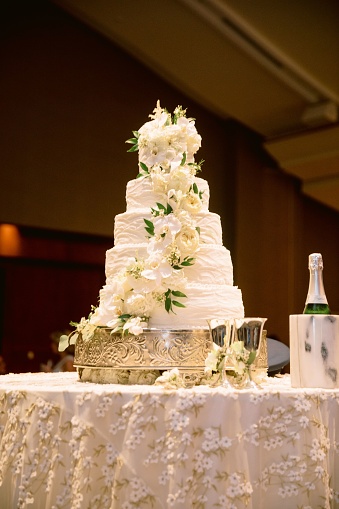 A selective focus shot of a stunning white wedding cake decorated with flowers on the table