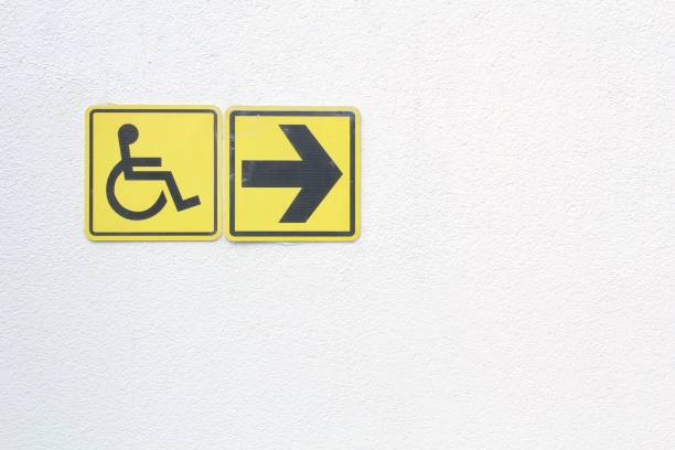istock Yellow disabled sign and arrow right pointing sign on white background. Handicapped accessible sign of wheelchair 1453093805