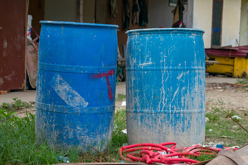 Two blue plastic drums, water container, at outside warehouse
