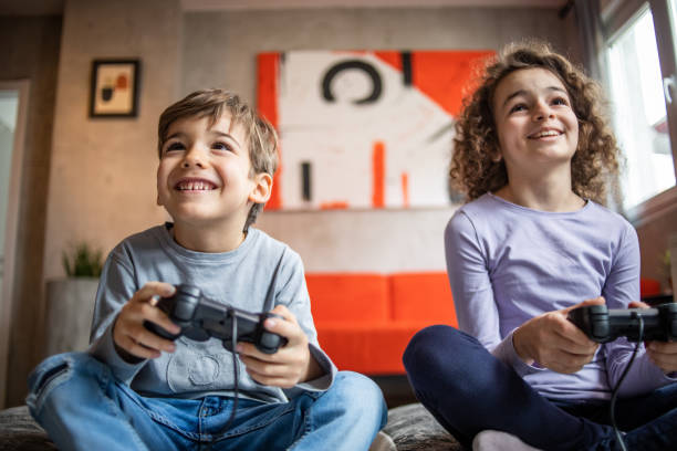 Two little kids, brother and sister play video game console using joystick stock photo