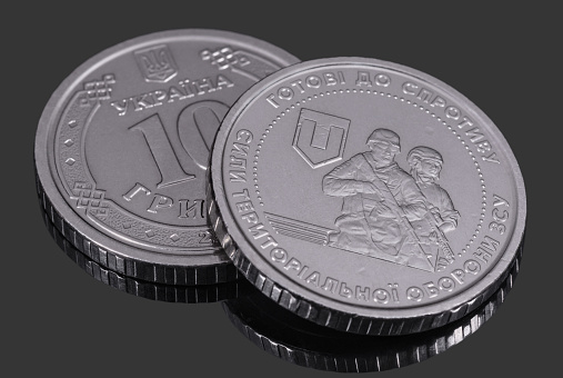 Commemorative coin 10 hryvnia Territorial Defense Forces of the Defense Forces of Ukraine on dark mirror background. Money and finance