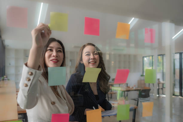 istock Confident businesswomen planning while looking at adhesive notes stuck on a glass wall. 1453100628