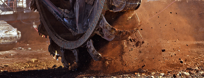 Bucket-wheel excavator during excavation at the surface mine. Huge excavator on open pit mine.