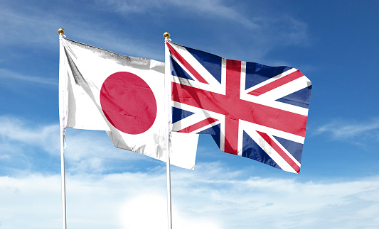 Flags of Japan and Great Britain against cloudy sky. waving in the sky