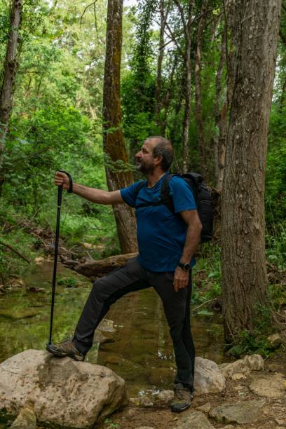istock man standing on a river with backpack and walking stick looking at the horizon 1453104263