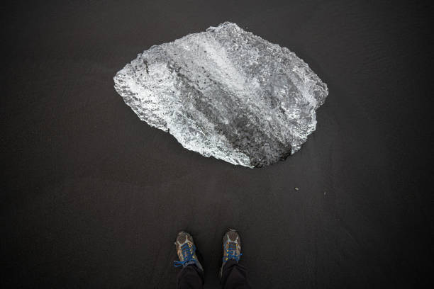 Feet selfie on black sand beach with diamond ice blocks, Iceland.