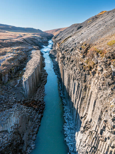 istock Studlagil canyon with turquoise water stream and basalt columns 1453105275