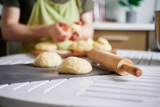 istock Dough preparation. Baker hand making dough balls on a table in kitchen 1453105617