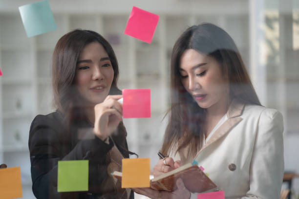 istock Confident businesswomen planning while looking at adhesive notes stuck on a glass wall. 1453111889