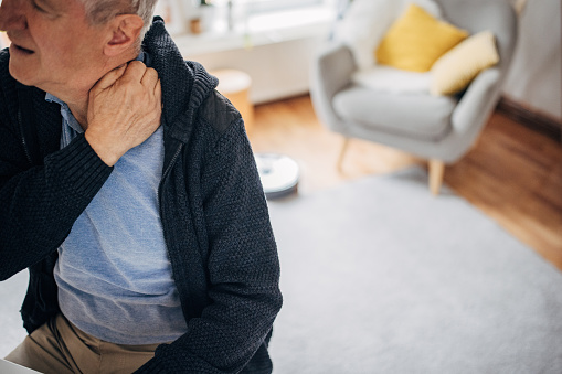 One man, old man having a neckache problems while sitting at home.