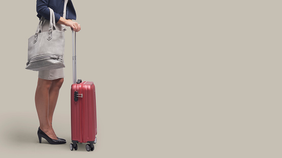 Elegant businesswoman traveling with a red trolley bag, business travel concept, blank copy space