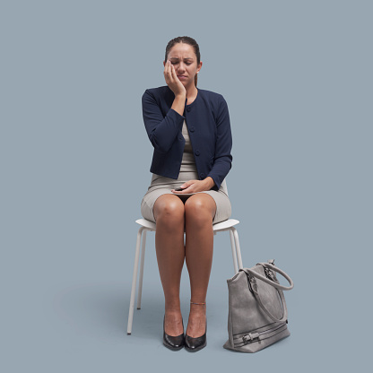 Woman sitting on a chair and touching her cheek, she is having a bad toothache, dentist and dental care concept