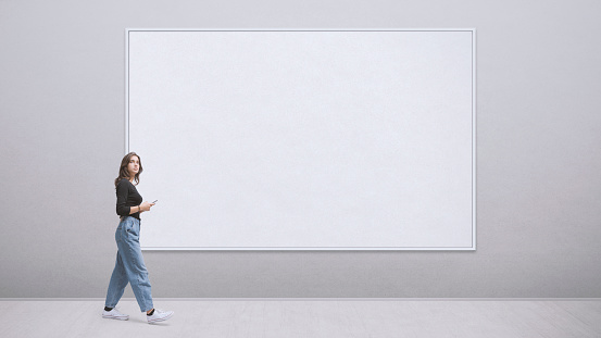 Young woman walking in the art gallery, she is looking at the paintings, blank copy space