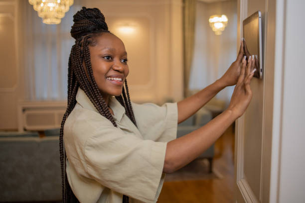 istock Young woman adjusts the temperature at home with a device on the wall 1453119801