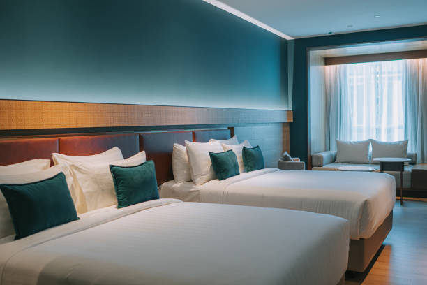 modernes hotelzimmer mit doppelbett, nachttischen und tagesschlafsofa - cushion pillow textile luxury stock-fotos und bilder