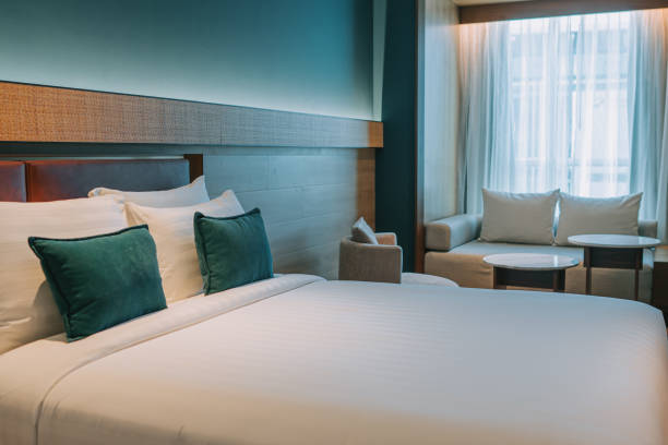 nowoczesny pokój hotelowy z podwójnym łóżkiem, stolikami nocnymi i rozkładaną sofą - double bed headboard hotel room design zdjęcia i obrazy z banku zdjęć