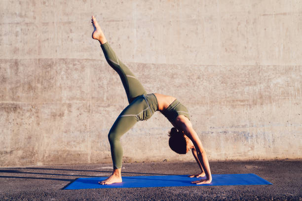 istock Young woman making Wheel pose with extended leg 1453121944