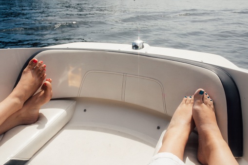 Woman reading magazine while sitting on sun lounger on luxury yacht.