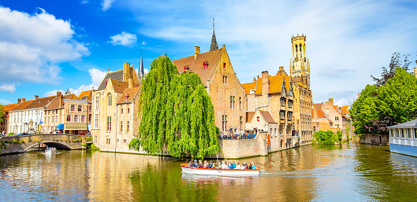 Bruges, Belgium - 17 May, 2022: Brugge old town scenic view, water canal and boat with tourists