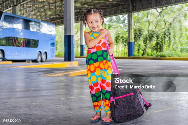 Little Latina Girl With A Big Bag Waiting For A Bus At The Bus Station 