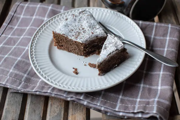 Traditional italian chocolate, almond cake. Torta caprese. Baked with dark and grated chocolate. Served ready to eat on a white plate with fork on wooden background with copy space