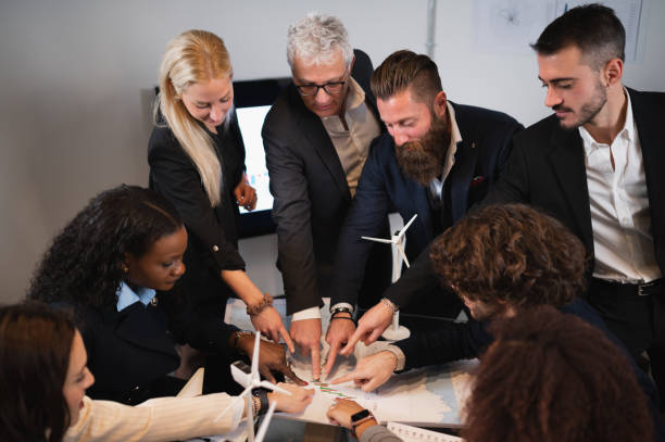 istock Group of business people with different ethnicity in office pointing at a chart. Teamwork planning a new project idea. 1453128392